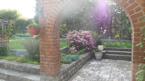 A brick archway leading to a garden with potted plants and flowering shrubs. - Vallée des Prés by Interhome (Mesnil-Saint-Blaise)