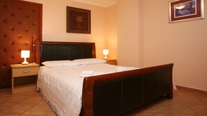 A neatly made bed with white linens, two bedside tables with lamps, a wooden headboard, and a framed picture on the wall. - 1573593 by Interhome (Poreč)