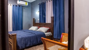 A bedroom with two beds, a wooden headboard, a wicker chair, and a ceiling-mounted air conditioner. - Clean beds, Sound Sleep (Accra)