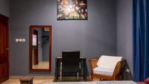 Een slaapkamer met een bed, een bureau, een stoel, een spiegel en een schilderij aan de muur.