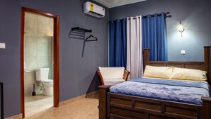 Een slaapkamer met een houten bed, een hangstoel, een douche en een toilet.