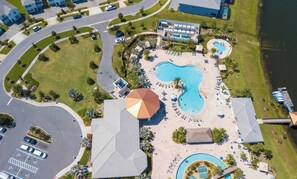 Ein Luftbild eines Resorts mit mehreren Schwimmbecken, darunter ein großes zentrales Becken, und einem Parkplatz.