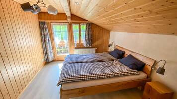 Une chambre à coucher dans un chalet en bois, avec un lit, deux lampes de chevet et une fenêtre avec des rideaux.