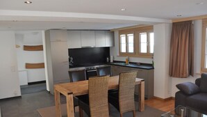 Een moderne keuken met een eethoek, met een houten tafel en rieten stoelen.