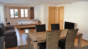 Een moderne kamer met een bed, een slaapbank, een eettafel met stoelen en een televisie.