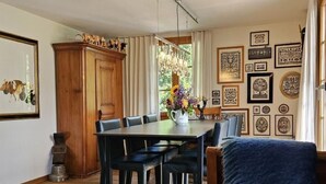 A dining area with a wooden table and chairs, a chandelier, and a blue sofa. - Chalet Tannegüetli by Interhome (Grindelwald)