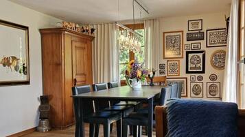 Un coin repas avec une table et des chaises en bois, un lustre et un canapé bleu.