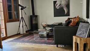 A living room with a fireplace, a telescope, a rug, a couch, and a coffee table. - Chalet Tannegüetli by Interhome (Grindelwald)