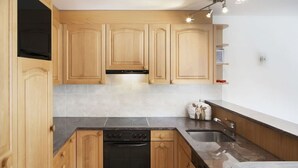 Una cocina moderna con armarios de madera, una estufa negra y una encimera de granito.