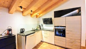 A compact kitchen with wooden beams, a built-in oven, and a microwave.