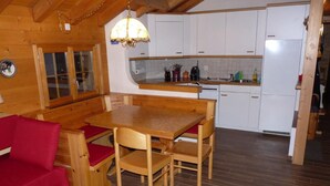 Een gezellig houten chalet met een eethoek, keuken en een rode bank.