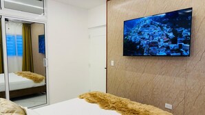 A modern hotel room with a large bed, a television mounted on the wall, and a mirror reflecting the room. - sol y arena bayahibe (Bayahíbe)