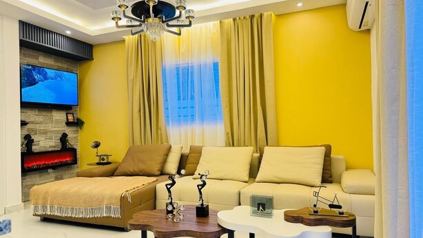 A modern living room with a sofa set, a fireplace, and a TV mounted on the wall. - sol y arena bayahibe (Bayahíbe)