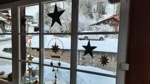 A window with star decorations and a view of a snowy landscape with houses. - Eschengasse 21 by Interhome (Grindelwald)
