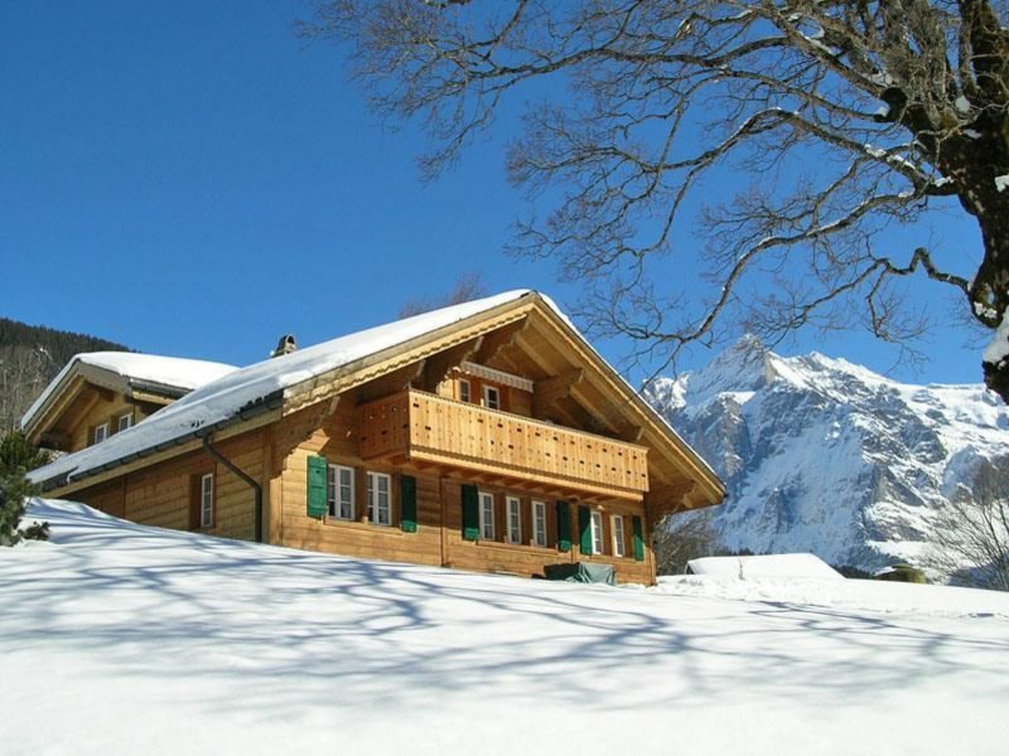 Eine Holzhütte mit Balkon, umgeben von Schnee und Bergen.