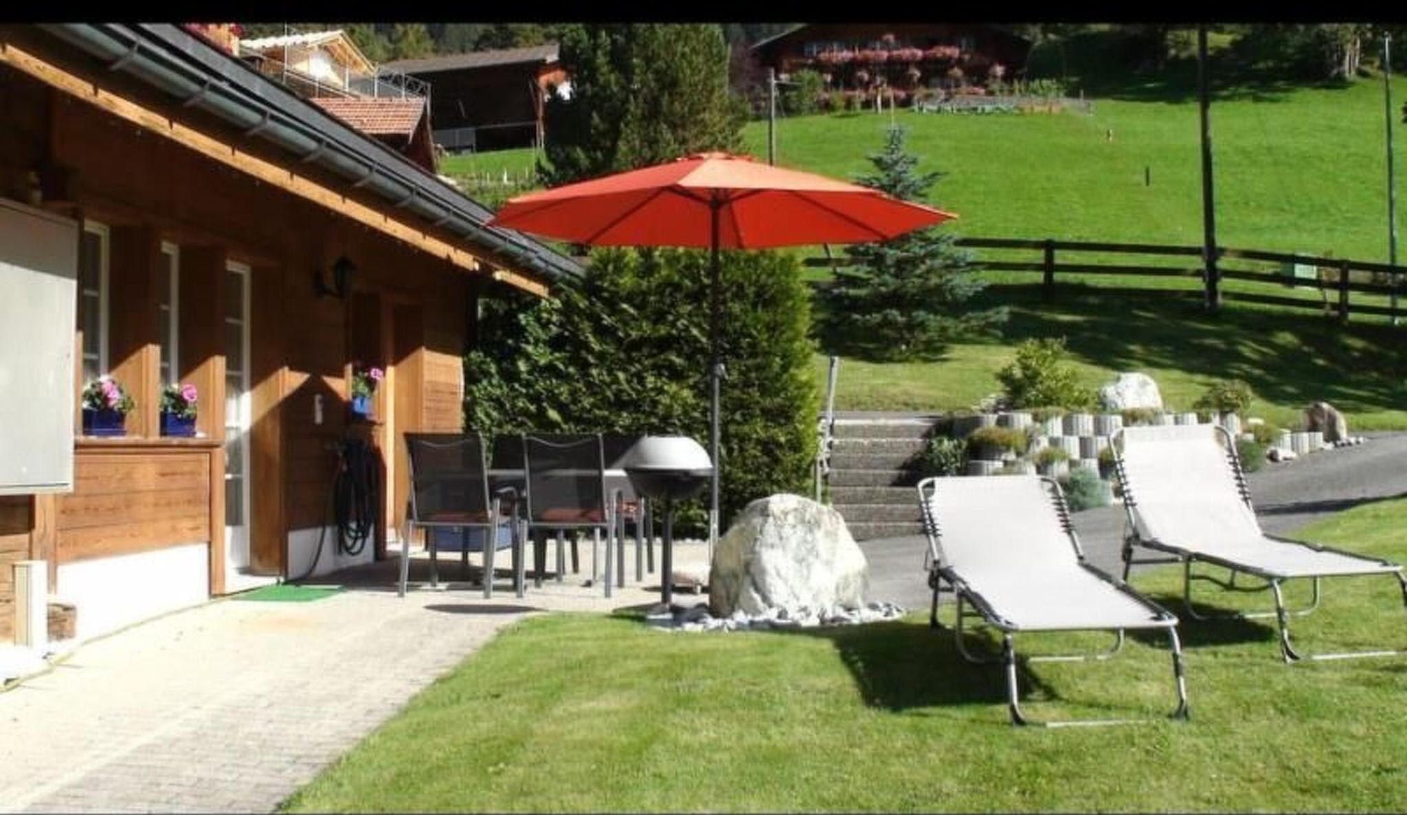 A wooden building with a patio area featuring outdoor seating and a barbecue grill.