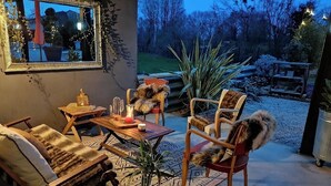 Eine Terrasse im Freien mit Holzmöbeln, einem Spiegel und Topfpflanzen.