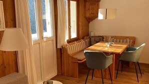 A cozy dining area with a wooden table, cushioned bench seating, and two chairs. - Chalet Bachsbort 14 by Interhome (Grindelwald)