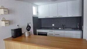 A kitchen with white cabinets, a wooden countertop, a stove, and a sink. - Chalet Bachsbort 14 by Interhome (Grindelwald)