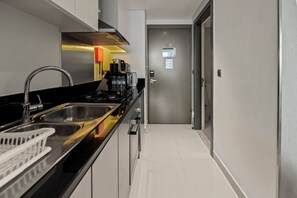 Et moderne køkken med stålemmer, bordplade i sort og klinkegulv i hvid.