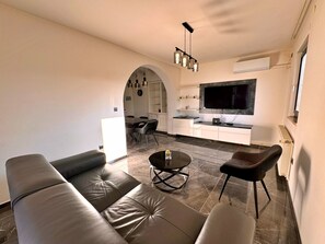 A modern living room with a sofa, a coffee table, and a TV in the background. - Apartment Katarina by Interhome (Krk/Milohnići)
