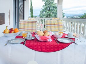 A breakfast table set with fruits, bread, and beverages on a balcony with a scenic view. - Familienwohnung in Malinska by Interhome (Krk/Milohnići)