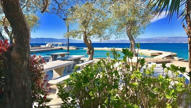 Ett poolområde med solstolar och utsikt över havet.