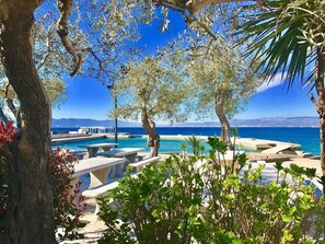 A pool area with lounge chairs and a view of the sea. - Familienwohnung in Malinska by Interhome (Krk/Milohnići)