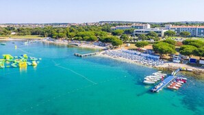 Ein Luftbild einer Küstenregion mit einer Marina, einem Strand und Gebäuden.