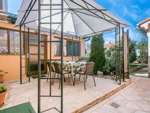 A covered patio with a table and chairs, surrounded by a garden and a building. - Apartment "Arijana2" mit privater Terrasse by Interhome (Medulin)