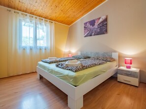 A bedroom with a wooden ceiling, a bed with leopard print bedding, a bedside table with a lamp, and a window with sheer curtains. - Apartment "Arijana2" mit privater Terrasse by Interhome (Medulin)