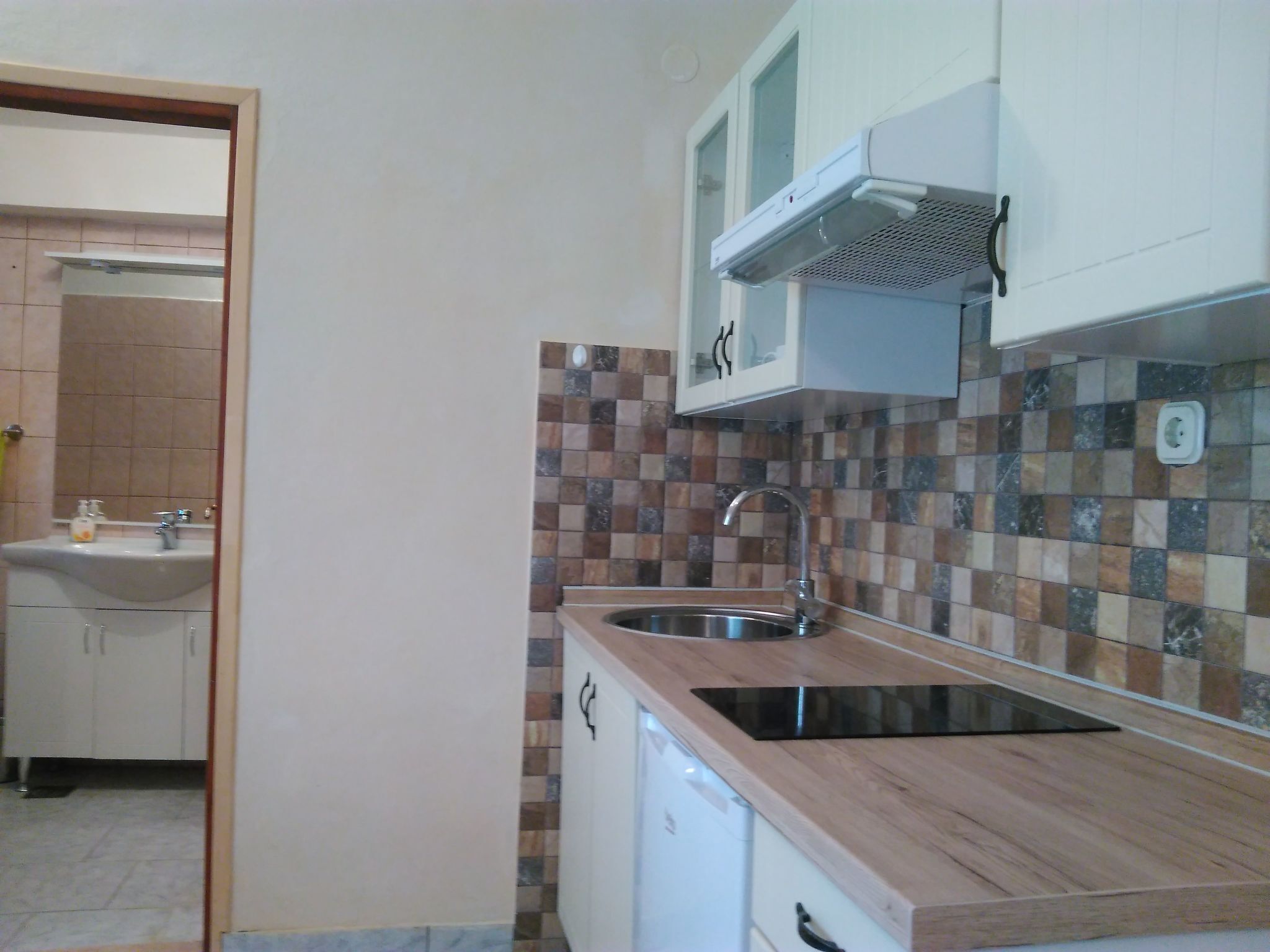 Una cocina compacta con encimera de madera, pileta integrada y microondas.