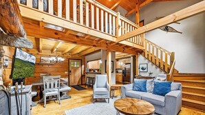 Un espacio habitable amplio con una escalera de madera, una mesa de comedor y un sofá.