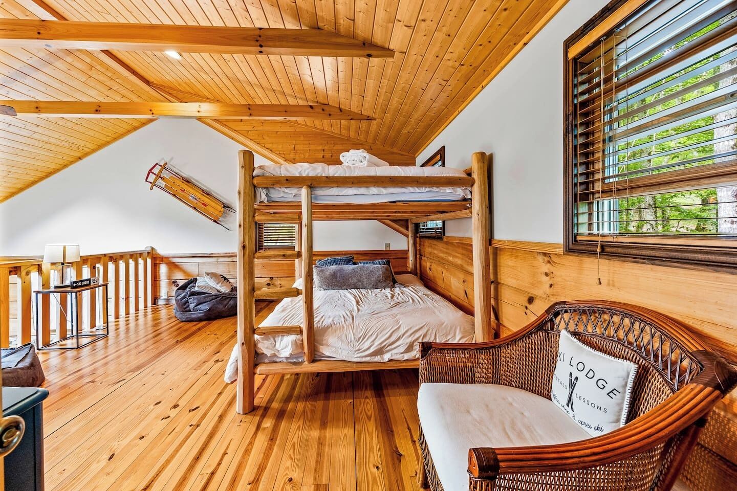 Une chambre avec un lit superposé en bois, donnant sur un paysage verdoyant.