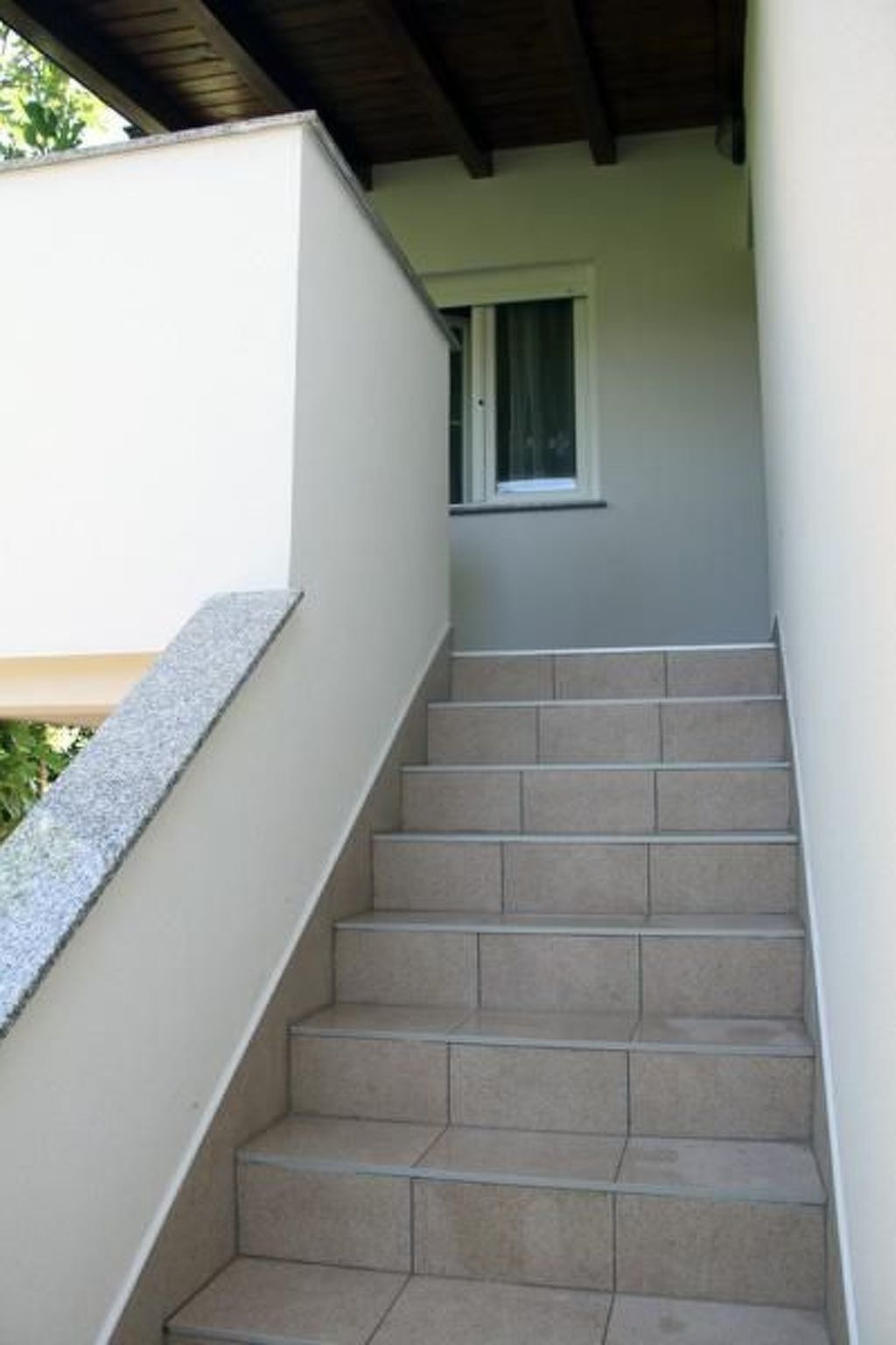 A staircase with beige steps leading to a window.