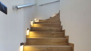 Una scala in legno con illuminazione integrata, una ringhiera e una finestra in cima.