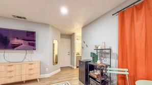 Un salon moderne doté d’un téléviseur à écran plat, de meubles en bois, d’un coin café et d’un tapis coloré.