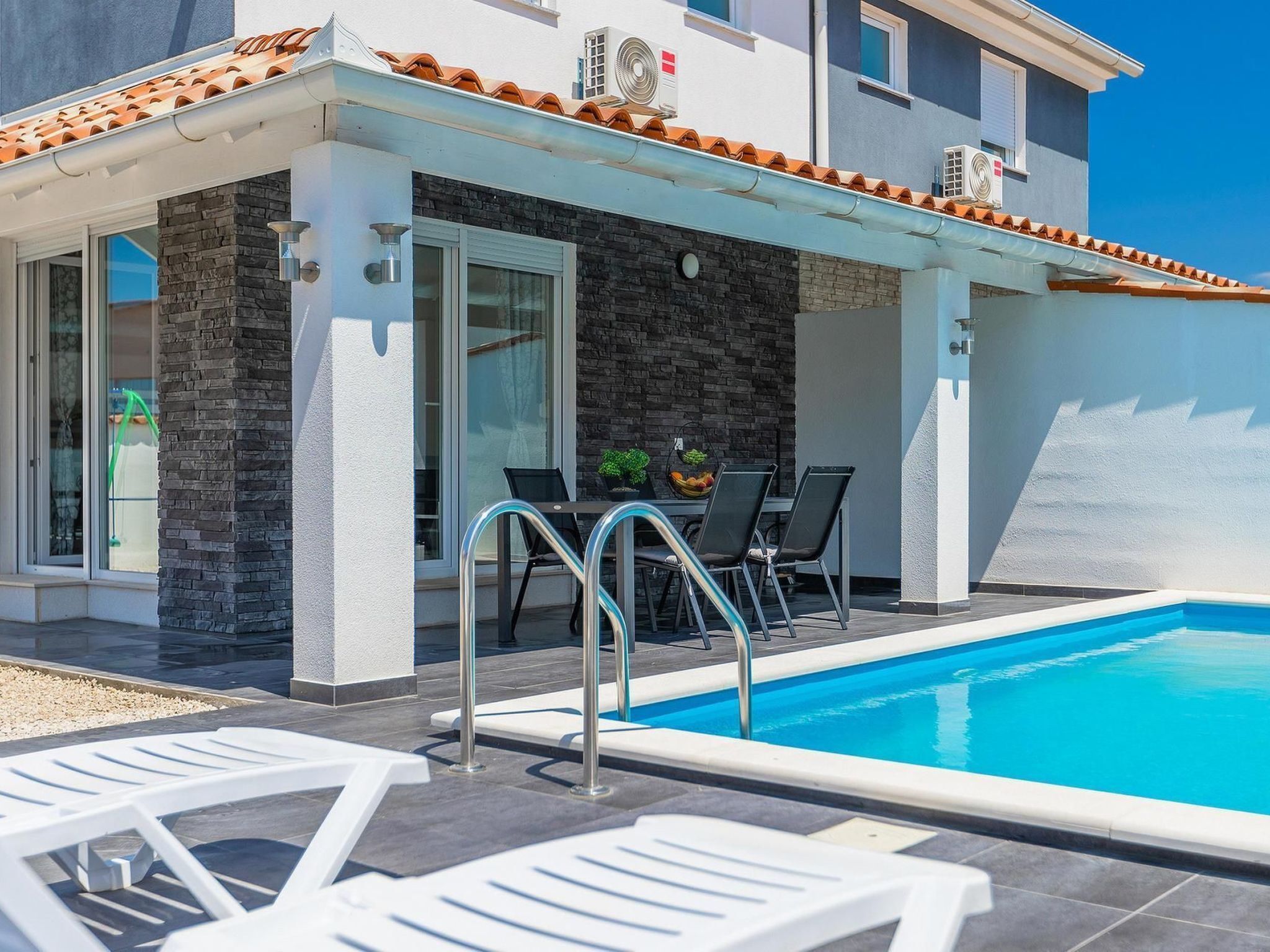 Un edificio moderno con piscina, area relax all'aperto e facciata in pietra.