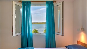 A bedroom with a bed, a view of a body of water, and teal curtains. - direkt am Strand by Interhome (Medulin)