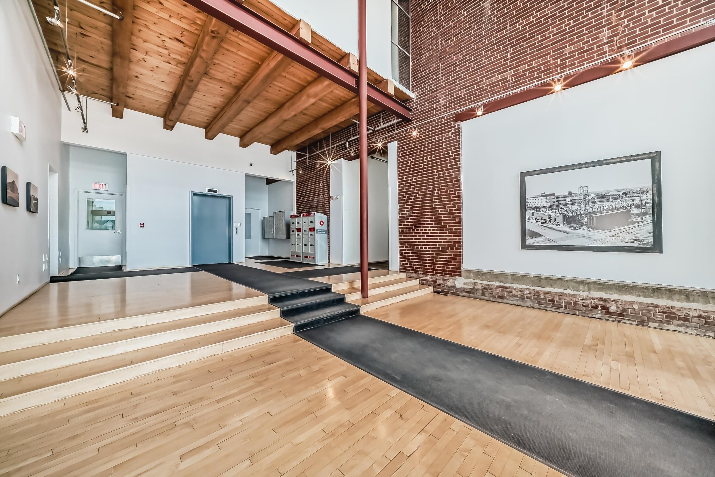 Un interno moderno con pavimento in legno, una scala e un muro in mattoni con un quadro incorniciato.