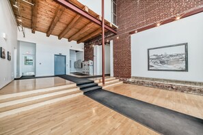 Un interior moderno con piso de madera, una escalera y una pared de ladrillo con un cuadro enmarcado.