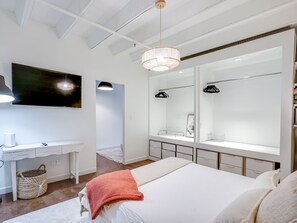 Una camera da letto moderna con un letto grande, una toeletta con uno specchio e un televisore montato a parete.