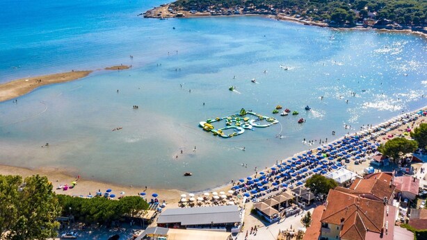 Una zona costera con playa, parque acuático y edificios.