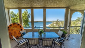 A covered patio with a table and chairs, large windows with a view of the sea, and a patterned floor. - Island on Lake Travis | Labor Day Weekend availability! Filling up quick! (Lago Vista)