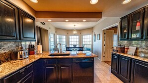 A spacious kitchen with dark cabinetry, granite countertops, and a central island. - Island on Lake Travis | Labor Day Weekend availability! Filling up quick! (Lago Vista)