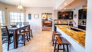 A spacious kitchen with a large island, dark wooden dining table, and chairs. - Island on Lake Travis | Labor Day Weekend availability! Filling up quick! (Lago Vista)