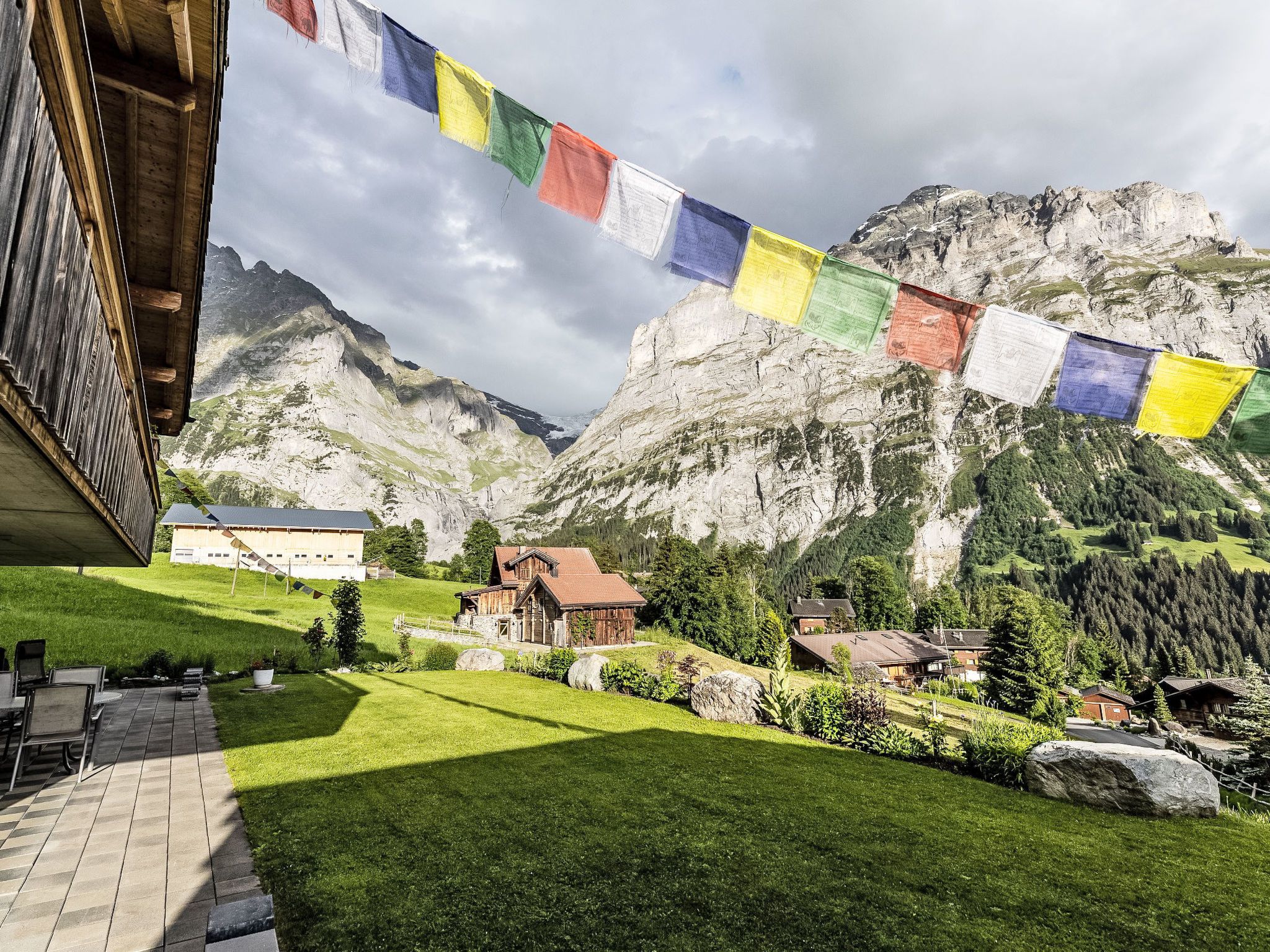 A mountainous landscape with a wooden building and a row of colorful prayer flags.