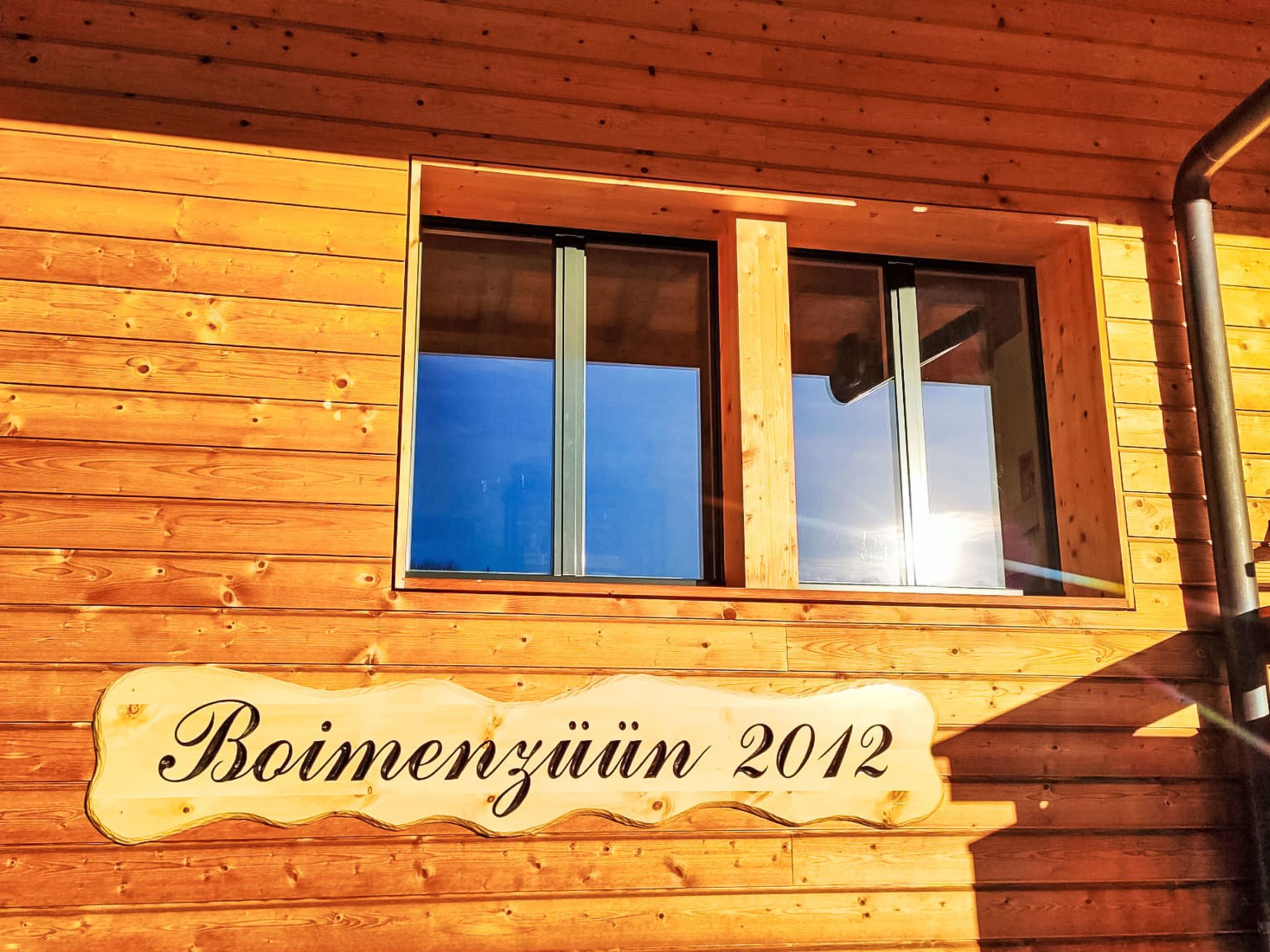 Eine Holzhütte mit einem Fenster und einem Schild, auf dem 'Boimenzüin 2012' steht.