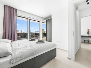 Un dormitorio moderno con una cama grande, vista al cielo y un balcón.