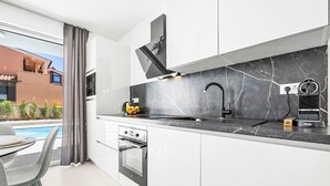 A modern kitchen with a black marble countertop, a built-in oven, and a black faucet. - Wohnung "Sladja lux Wohnung" by Interhome (Medulin)